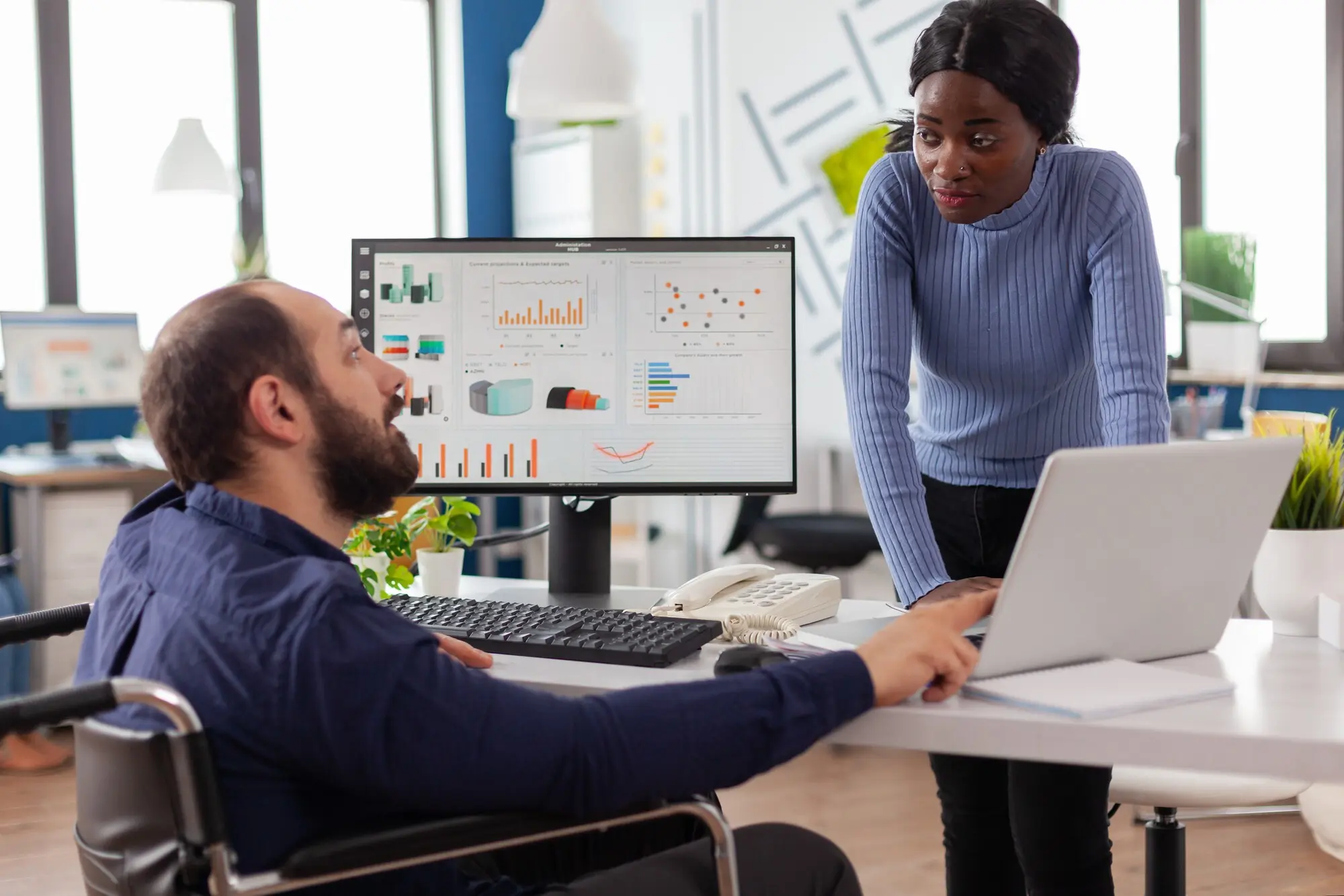 Geschäftsmann mit Behinderung und Mitarbeiter arbeiten gemeinsam an einem Finanzprojekt für ein Start-up-Unternehmen.