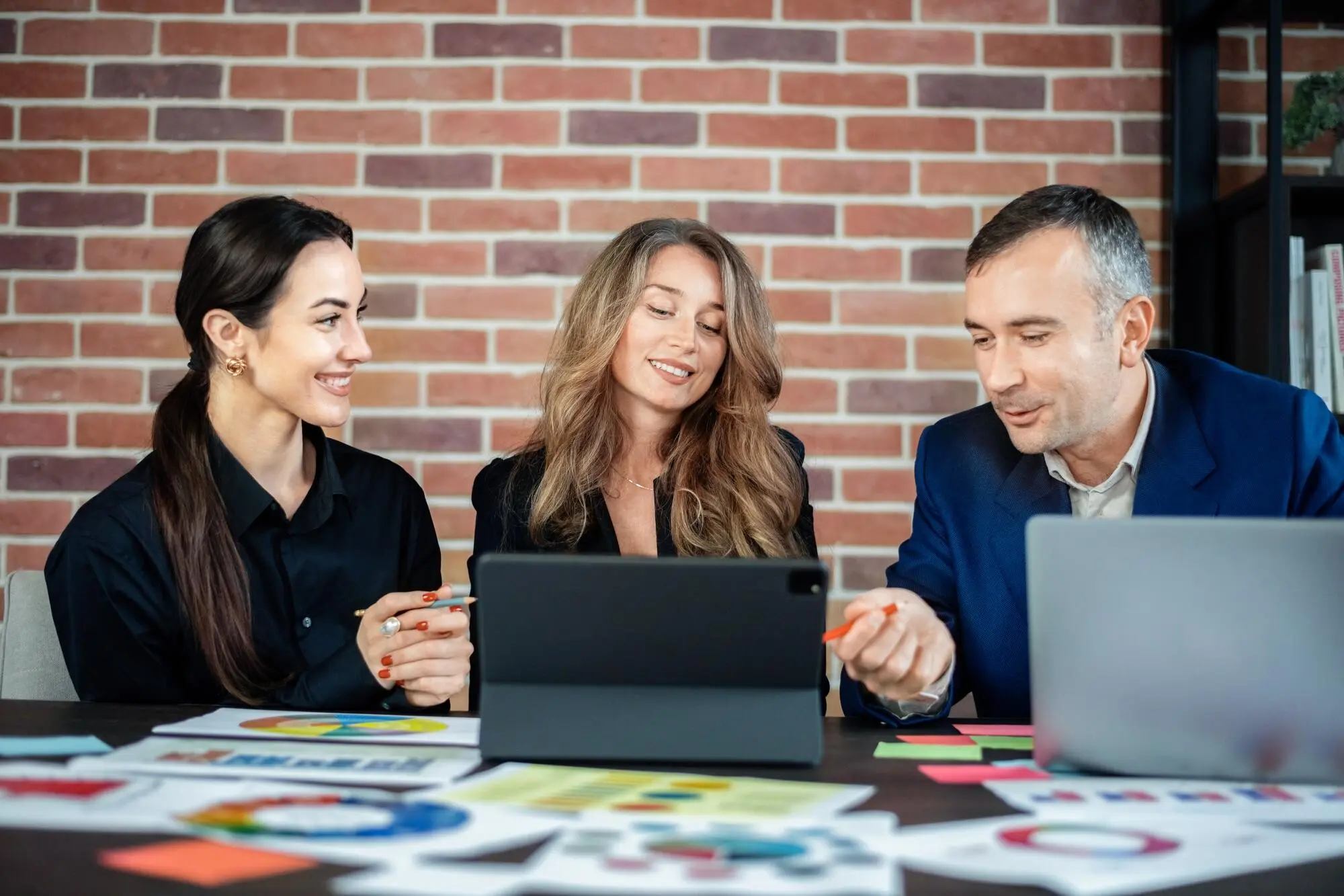 Geschäftssitzung im Büro: Frauen und ein Mann besprechen geschäftliche Angelegenheiten; Geräte und Papiere.